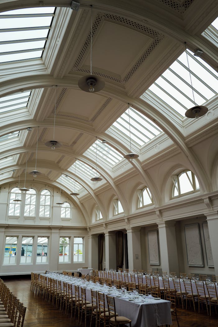 services-01 Spacious banquet hall featuring an elegant skylight ceiling and long dining tables, perfect for events.